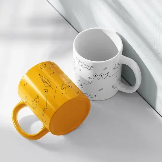 The Shiraz Collection mug in yellow and in white, resting on a sunlit windowsill